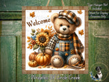 A teddy bear wearing a plaid hat and overalls, sitting next to a sunflower, pumpkins, and a dog, with the text "Welcome" and "Wreaths of Circle Creek" displayed.