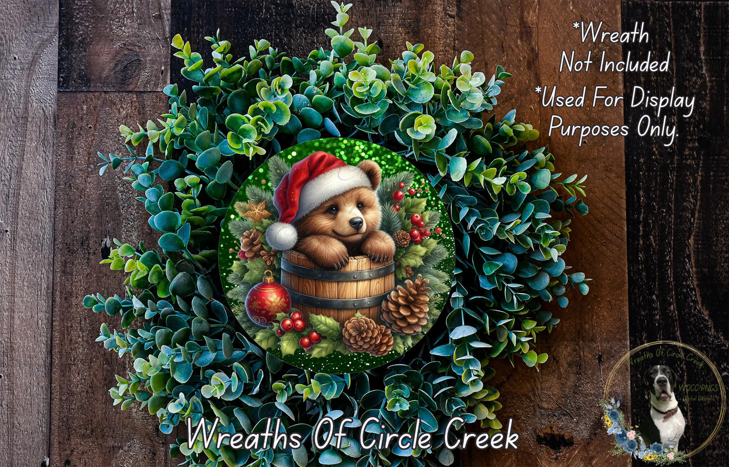 A wreath featuring a bear wearing a Santa hat, surrounded by pine cones, berries, and greenery, with a text overlay that reads "Wreath Not Included * Used For Display Purposes Only" and "Wreaths of Circle Creek".