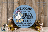 a blue sign with a cartoon goose and text, surrounded by flowers and a wooden background.
