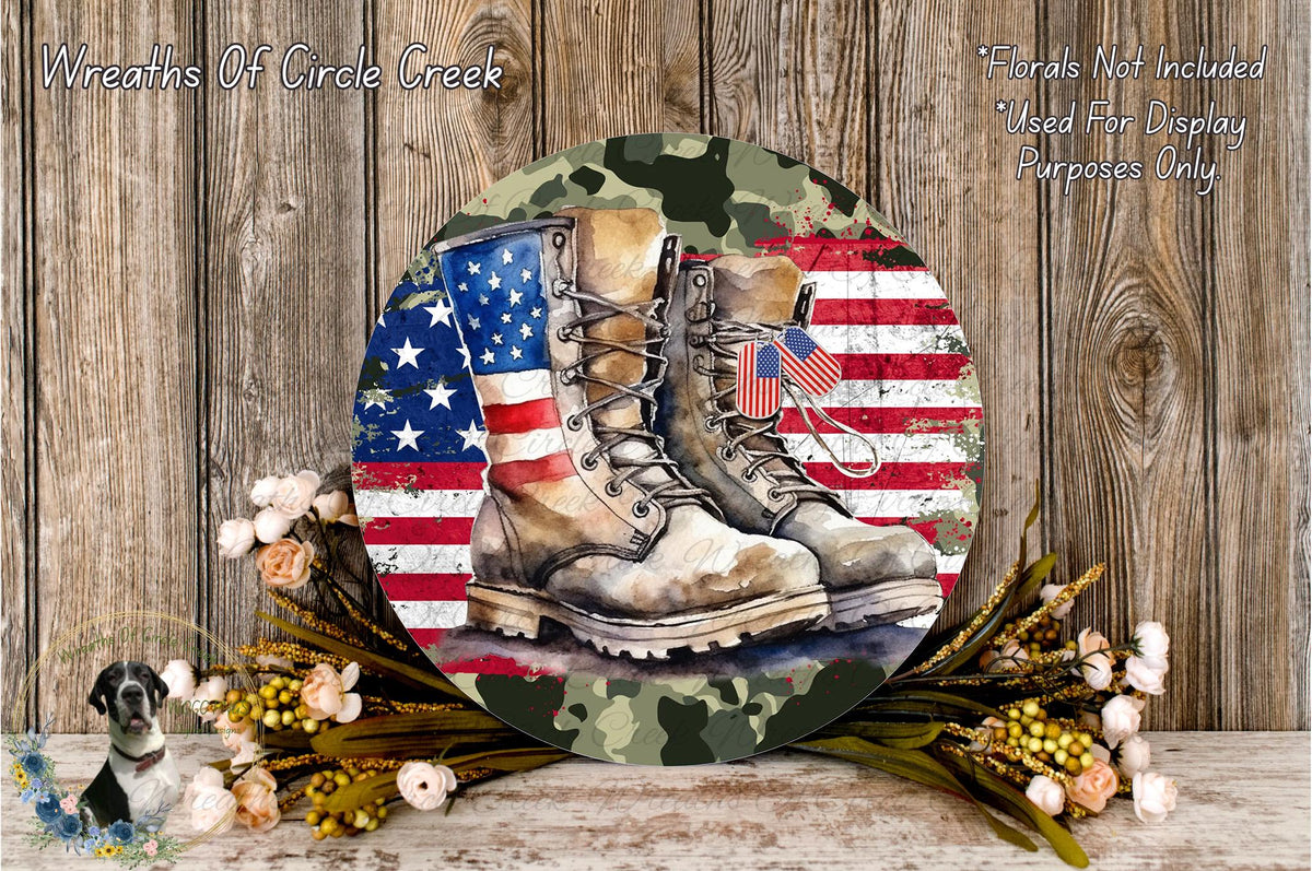 A circular wall decoration with a pair of worn boots in front of an American flag, surrounded by flowers and a camouflage pattern.
