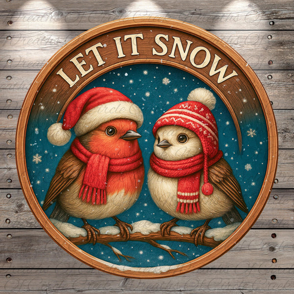 A circular wooden frame with a snowy winter scene inside, featuring two birds wearing red and white scarves and hats, with the text "LET IT SNOW" above them.