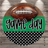 A football is placed on top of a green and black polka dot background with the text "game day" written in a stylized font.