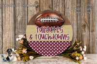 a decorative sign with a football and the words "tailgates & touchdowns" written on it, surrounded by a floral arrangement and a wooden background.