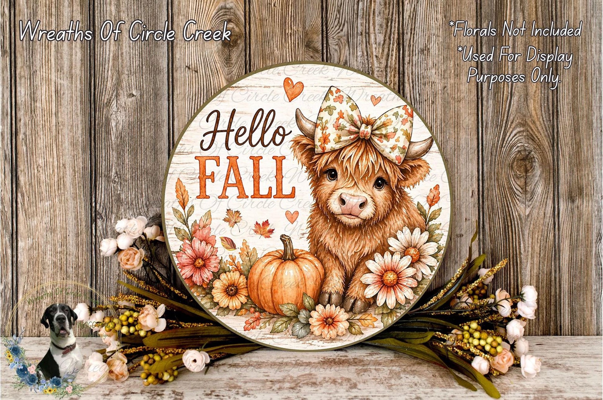 A decorative round sign with a cow wearing a bow and surrounded by autumn flowers and a pumpkin, with the text "Hello Fall" displayed on it.