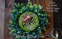 a wreath made of green foliage and a football, with the text "If we were not home, check the field" displayed on it.