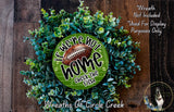 a wreath made of green foliage and a football, with the text "If we were not home, check the field" displayed on it.