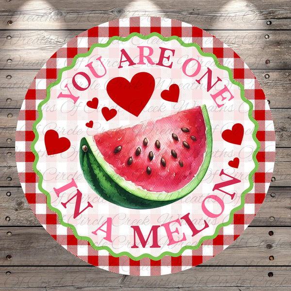 A round sign with a watermelon slice and hearts, surrounded by the text "YOU ARE ONE IN A MELON".