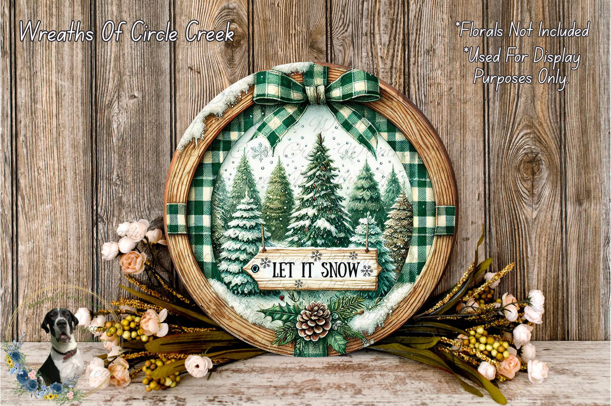 A wreath with a winter scene and the text "LET IT SNOW" is displayed on a wooden surface, surrounded by flowers and pine cones.