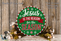 A circular sign with the text &quot;Jesus is the reason for the season&quot; surrounded by a wreath of flowers and greenery, placed on a wooden surface.