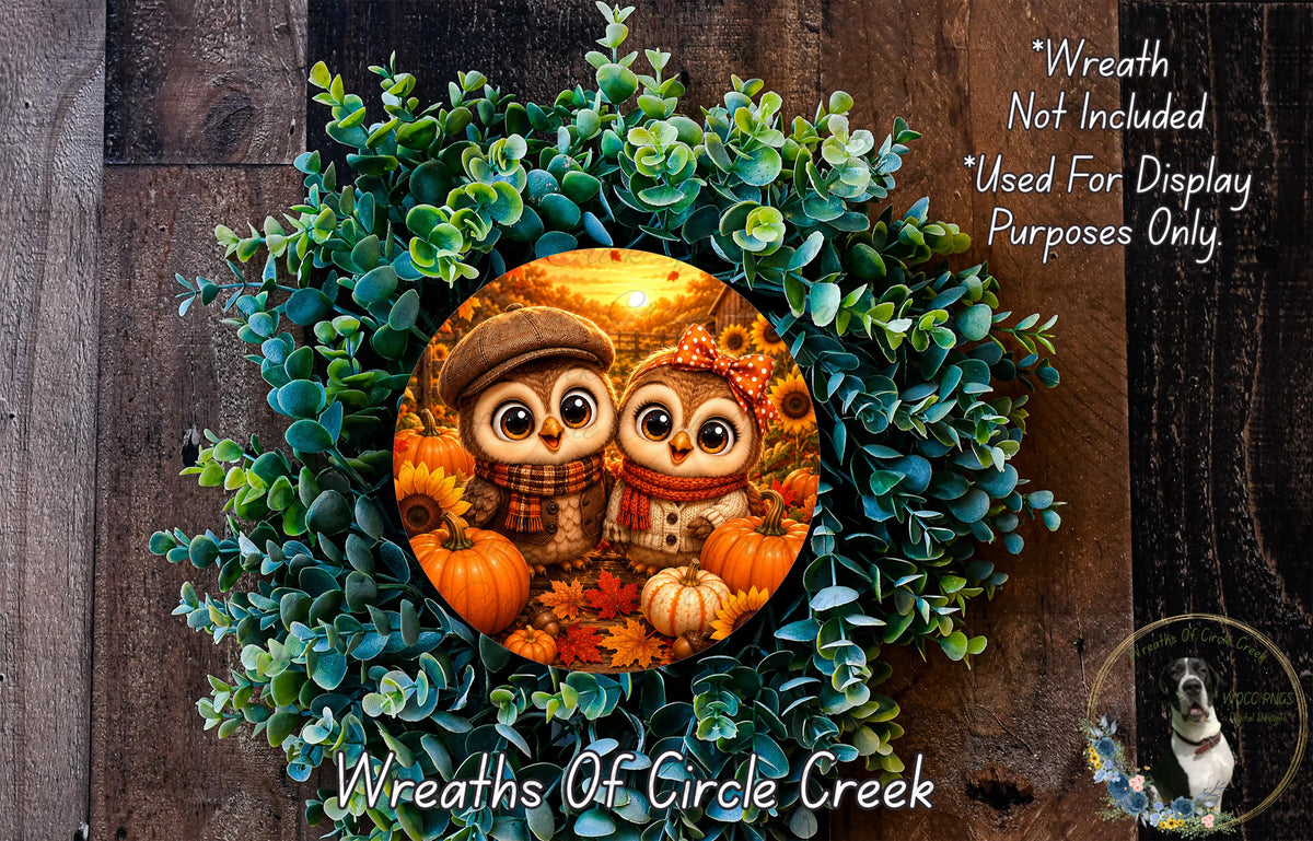 A wreath made of green leaves and autumn-themed pumpkins, featuring two cartoon owls wearing hats and scarves.