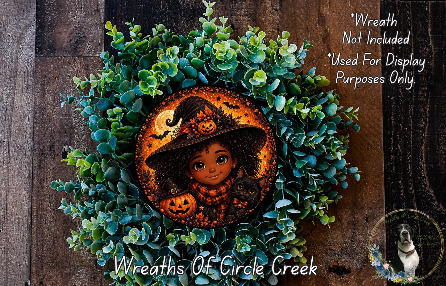 A wreath featuring a cartoon illustration of a young girl wearing a witch's hat, holding a pumpkin and a cat, surrounded by green foliage.