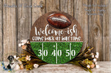 a welcome sign with a football on it, surrounded by a green glittery background and flowers. The sign reads "Welcome-ish Come back at half-time" and has a total of 30 and 40 yards displayed on it.