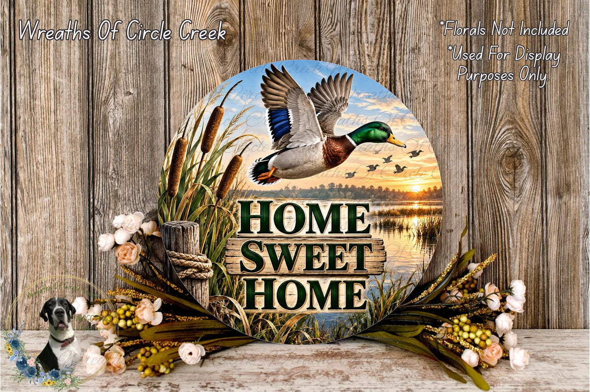 A decorative wreath with a duck flying over a sunset landscape, surrounded by flowers and greenery. The wreath has the text "HOME SWEET HOME" displayed on it.