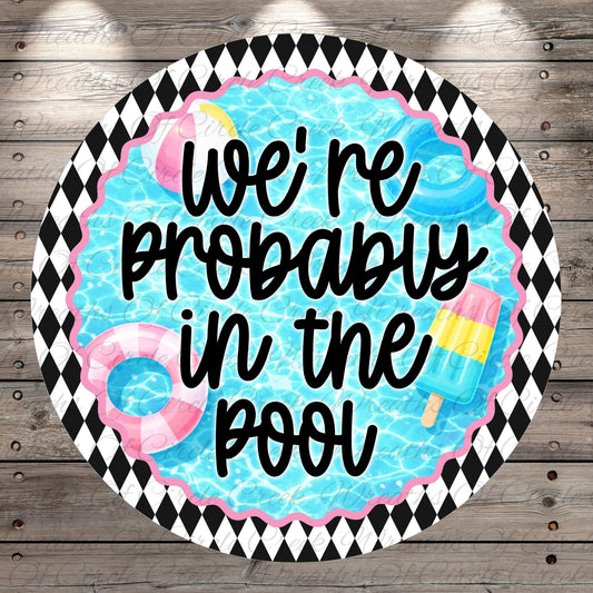 a circular design with a black and white diamond pattern around the edge, and a blue background with a water-themed illustration. The text "we're probably in the pool" is written in a playful, handwritten style.