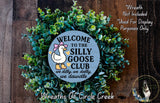 a wreath with a cartoon duck and the text "Welcome to the Silly Goose Club" surrounded by greenery.