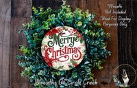 A wreath made of green and red foliage, with a circular sign that says &quot;Merry Christmas&quot; in the center.