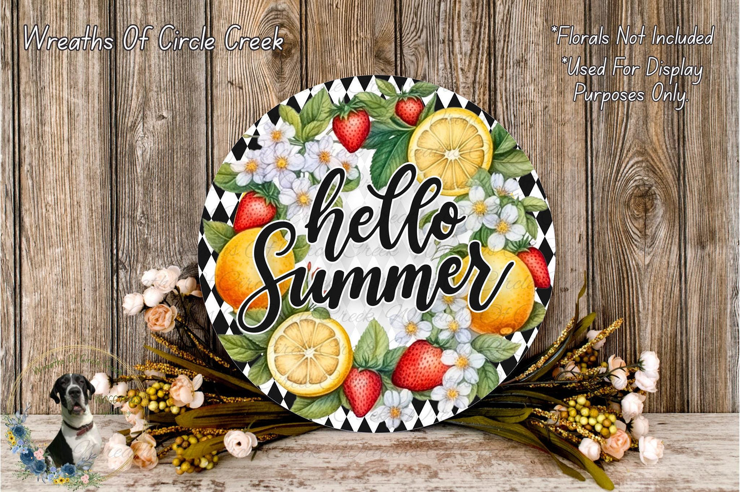 A decorative wreath with the text "Hello Summer" surrounded by various fruits and flowers, placed on a wooden surface.