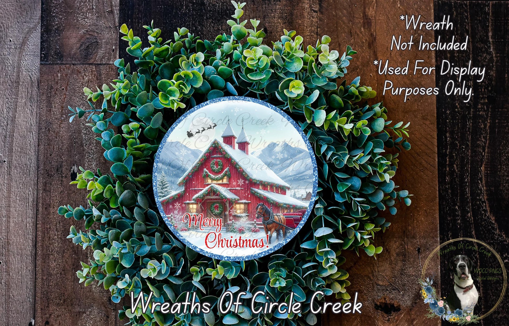 A Christmas wreath with a red barn and snowy mountain backdrop, surrounded by greenery. The wreath has a Santa Claus sleigh flying over the barn.