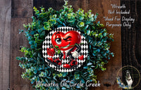a wreath with a red heart-shaped character wearing a suit and tie, surrounded by green foliage.