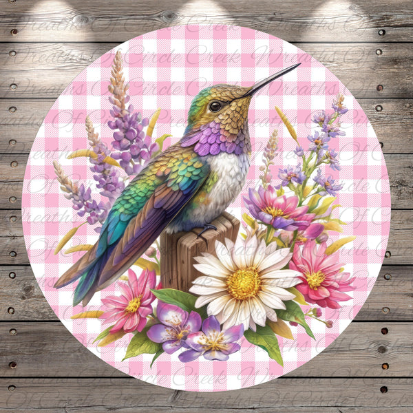 A colorful hummingbird perches on a wooden post, surrounded by a variety of flowers and foliage.