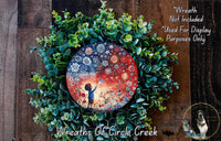 a wreath with a circular design, surrounded by a lush green wreath. The circular design has a depiction of a person holding a flag, and the wreath is adorned with various flowers and greenery.
