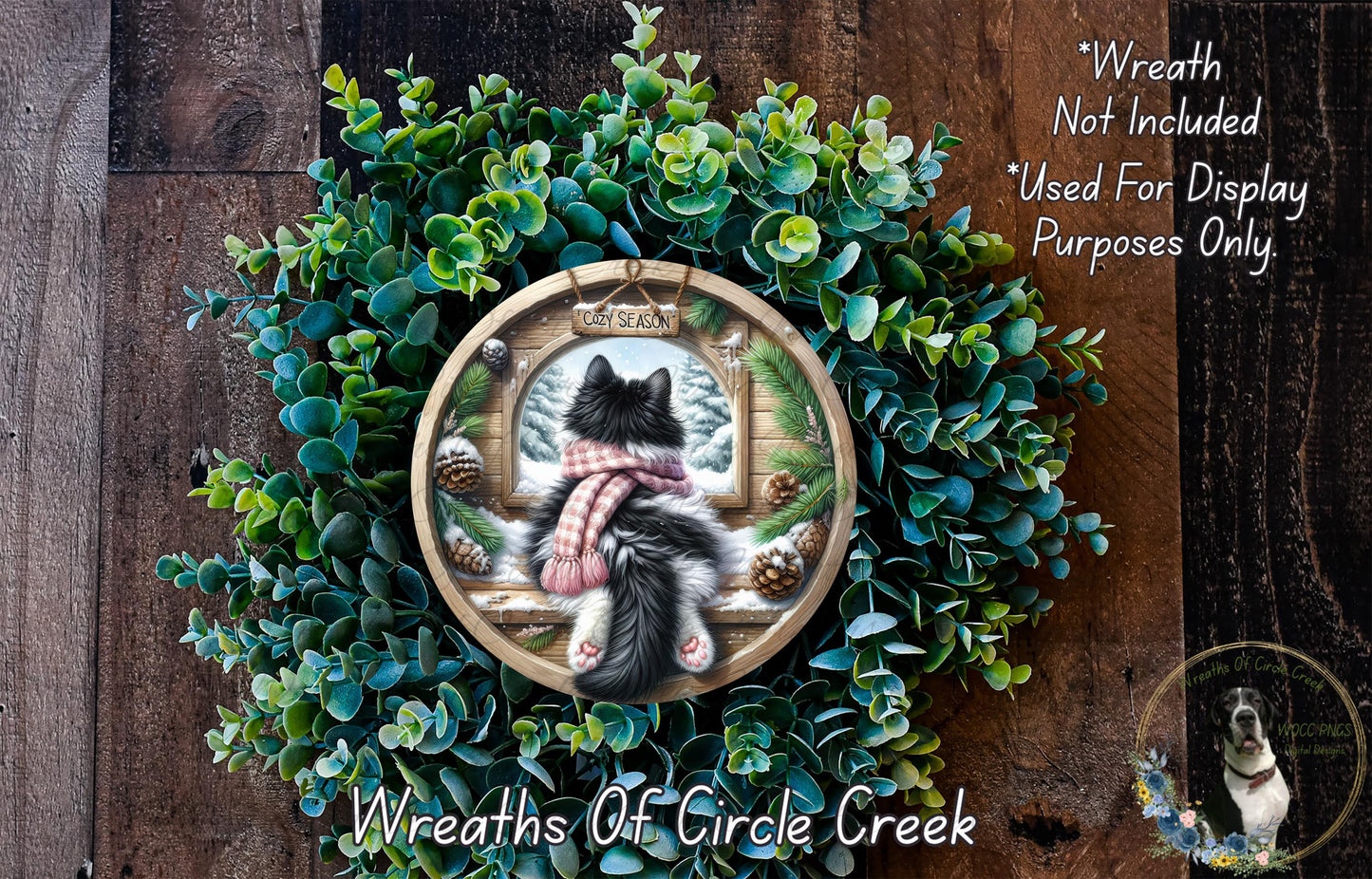 A wreath with a cat sitting in a window, surrounded by greenery, and a sign that says "Wreath Not Included Used For Display Purposes Only".