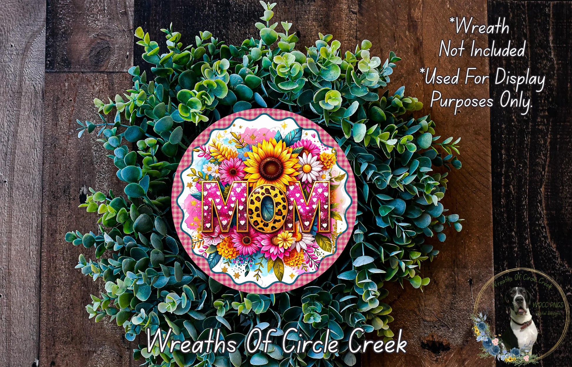 A wreath made of various green plants and flowers, with the word "MOM" prominently displayed in the center.