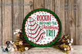 a festive Christmas tree decoration with the text "ROCKIN' AROUND THE CHRISTMAS TREE" displayed on it. The decoration is surrounded by a wreath of flowers, and the background is a wooden wall.