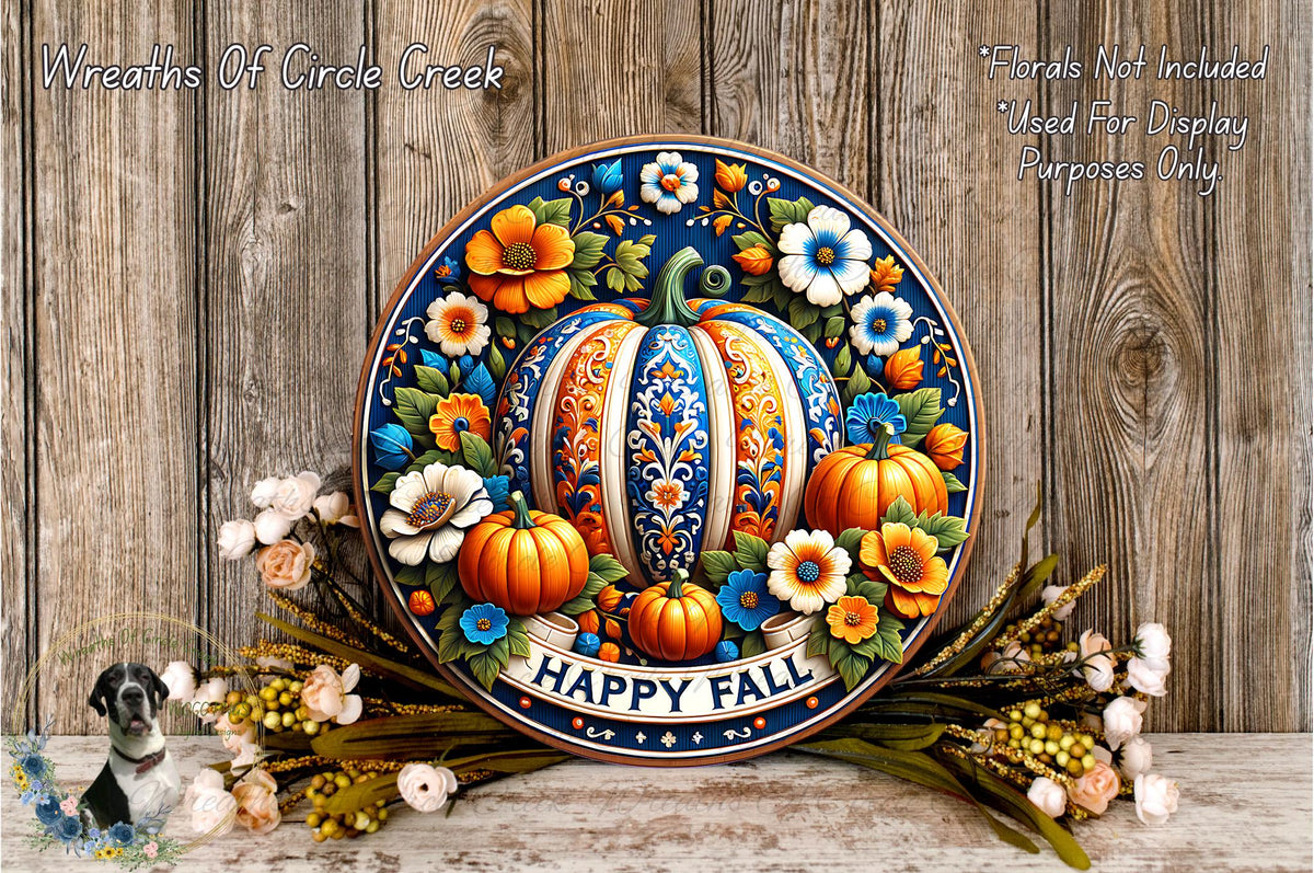 A decorative wreath with a pumpkin and flowers, surrounded by a floral arrangement, sits on a wooden surface.