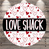a circular design with the text "LOVE SHACK" prominently displayed in the center. The design is set against a background of red hearts, creating a visually striking contrast.