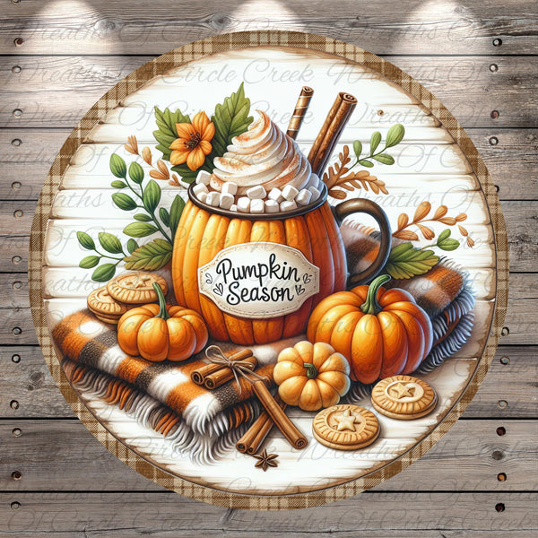 A round wooden sign with a pumpkin-themed design, featuring a pumpkin-shaped mug filled with whipped cream and marshmallows, surrounded by autumn-themed items such as pumpkins, cookies, and cinnamon sticks.