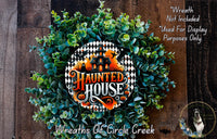 a wreath made of green leaves and a decorative house-shaped ornament, with the text "Haunted House" displayed prominently in the center.