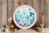 a decorative sign with the text "Sea You at the Beach" surrounded by a floral arrangement and a wooden background.