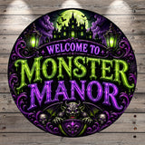 a circular sign with a dark, spooky, and Gothic-inspired design. The sign prominently displays the text "MONSTER MANOR" in a large, illuminated font, surrounded by various Gothic-style elements such as bats, skulls, and a castle. The overall design has a dark and mysterious atmosphere, suggesting a theme related to horror, Gothic architecture, or a supernatural setting.