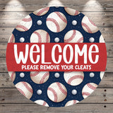 a circular sign with a baseball theme, displaying multiple baseballs and balls in various sizes and colors against a dark blue background. The sign also includes the text "Welcome Please remove your cleats" in a red banner.
