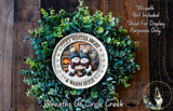 A wreath made of green leaves and featuring a snowman and a fireplace, with the text "COZY WINTER NIGHT & WARM HUGS" displayed on it.