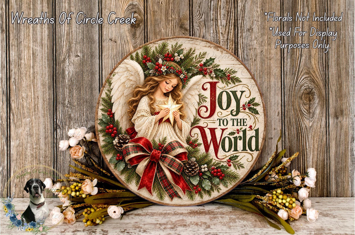 A round wooden plaque with a painted angel holding a star, surrounded by a wreath of flowers and greenery, and the text "Joy to the World".