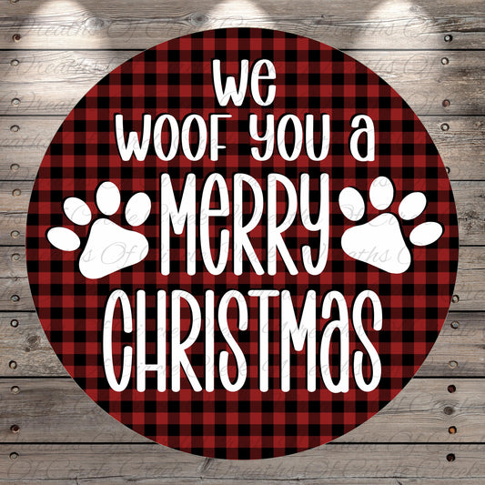 a circular design with a red and black plaid pattern and white text that reads "we woof you a merry Christmas".