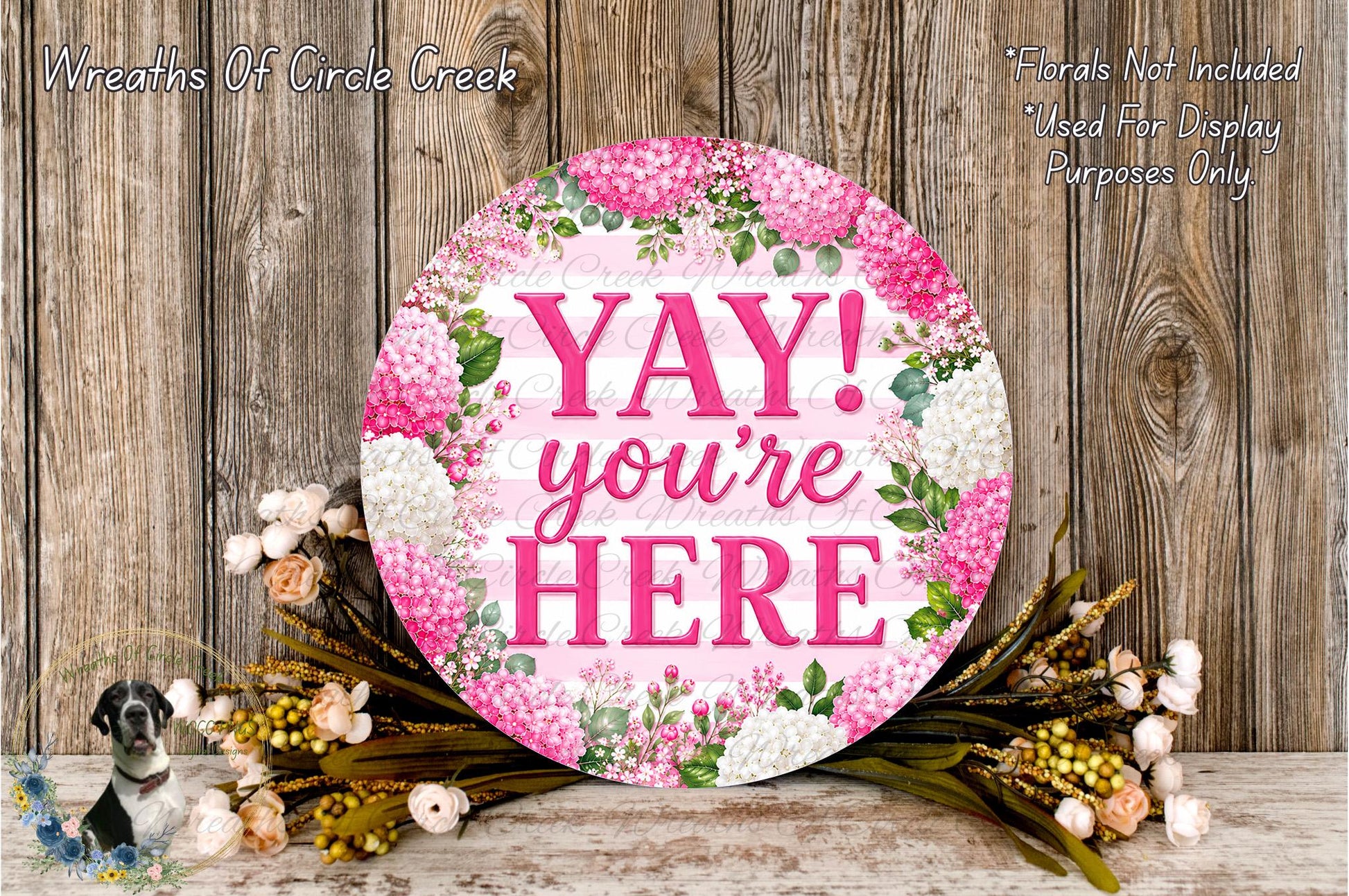 A round floral wreath with the text "YAY! you're here" in pink and white colors, surrounded by various flowers and greenery.
