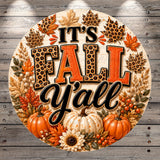 A decorative circular sign with the text "It's Fall Y'all" surrounded by autumn-themed elements such as leopard print leaves, pumpkins, and sunflowers.