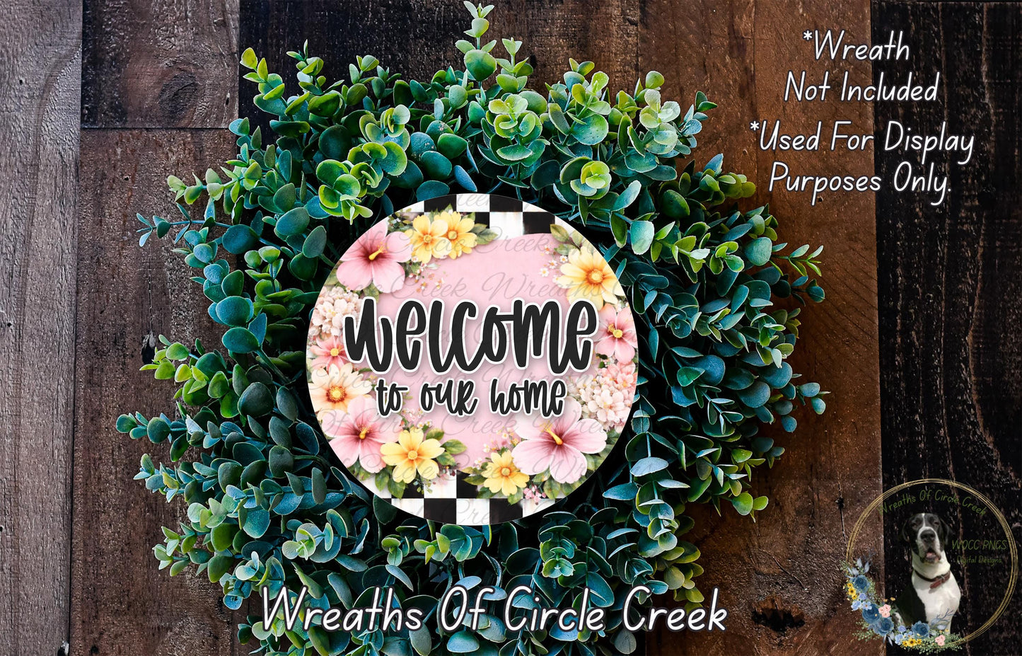 a wreath with a floral design and a sign that reads "Welcome to our home". The wreath is made of various green and pink flowers, and the sign is placed in the center of the wreath.