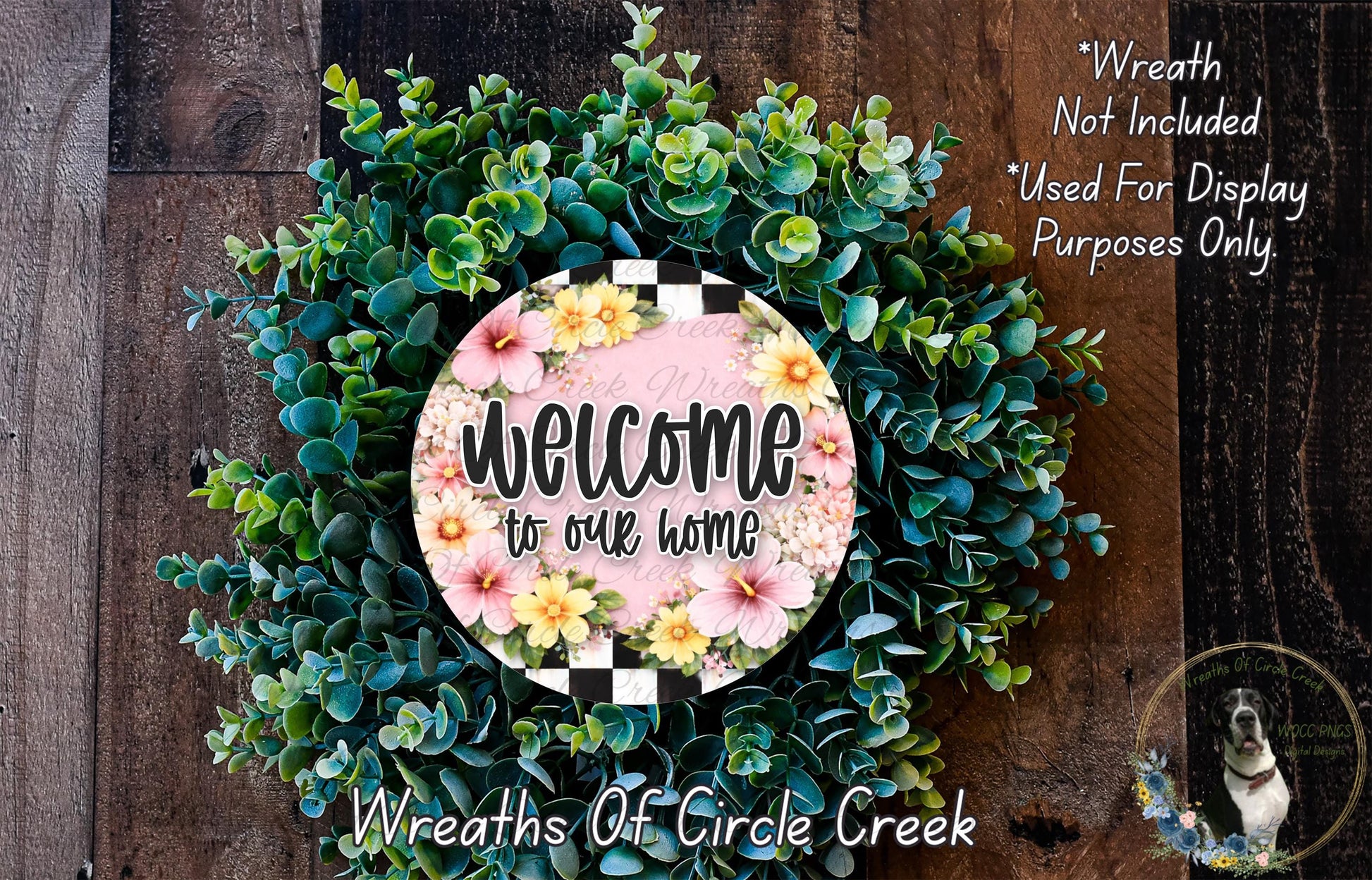 a wreath with a floral design and a sign that reads "Welcome to our home". The wreath is made of various green and pink flowers, and the sign is placed in the center of the wreath.