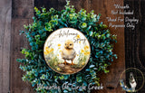 a wreath with a small duck and flowers, surrounded by a lush green wreath. The wreath is displayed on a wooden surface, and there is a text overlay that reads "Welcome Spring" and "Wreath Not Included Used For Display Purposes Only".
