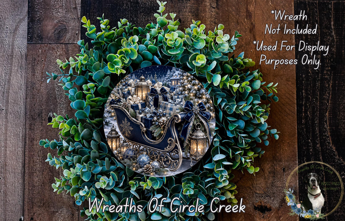 a wreath with a decorative sled and lanterns, surrounded by a lush green wreath. The wreath is placed on a wooden surface, and there is a small dog in the bottom right corner of the image.