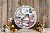 A decorative plate featuring a cat sitting on a pillow, surrounded by flowers and clothes, with a sign that says "Welcome Aboard" in the background.