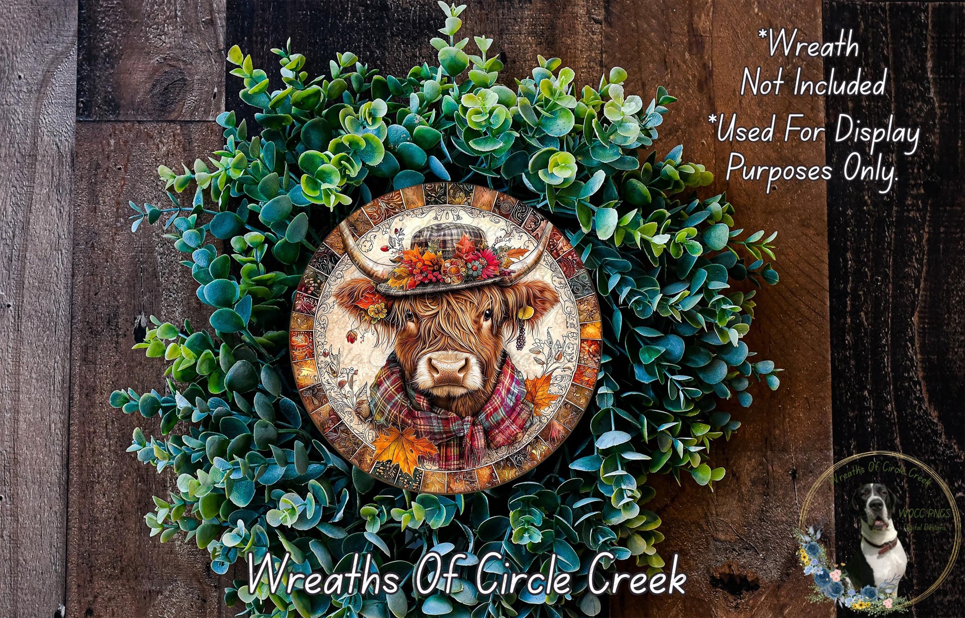 a wreath with a cow's head on it, surrounded by green leaves and flowers. The wreath is displayed on a wooden surface, and there is a small dog in the bottom right corner of the image.