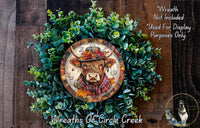 a wreath with a cow's head on it, surrounded by green leaves and flowers. The wreath is displayed on a wooden surface, and there is a small dog in the bottom right corner of the image.
