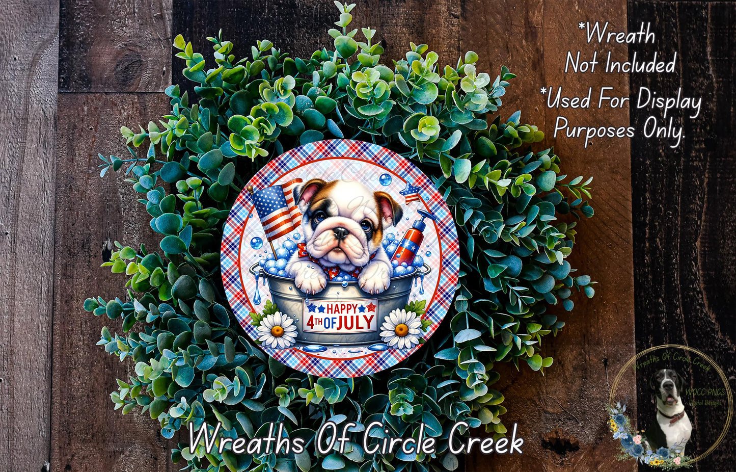 A wreath made of green leaves and flowers, featuring a bulldog in a bucket, with a patriotic American flag design. The wreath is displayed on a wooden surface, and there is a text overlay that reads "Wreath Not Included * Used For Display Purposes Only".