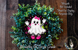 A wreath made of green foliage and featuring a ghost character with pink shoes and a bow, placed on a wooden surface.