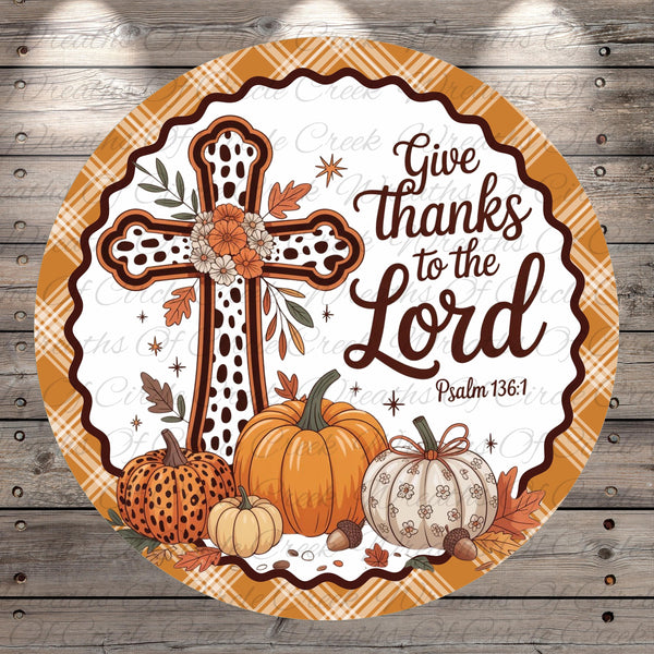 A circular wall hanging with a cross, pumpkins, acorns, and autumn leaves, along with the text "Give thanks to the Lord" and a Bible verse reference.
